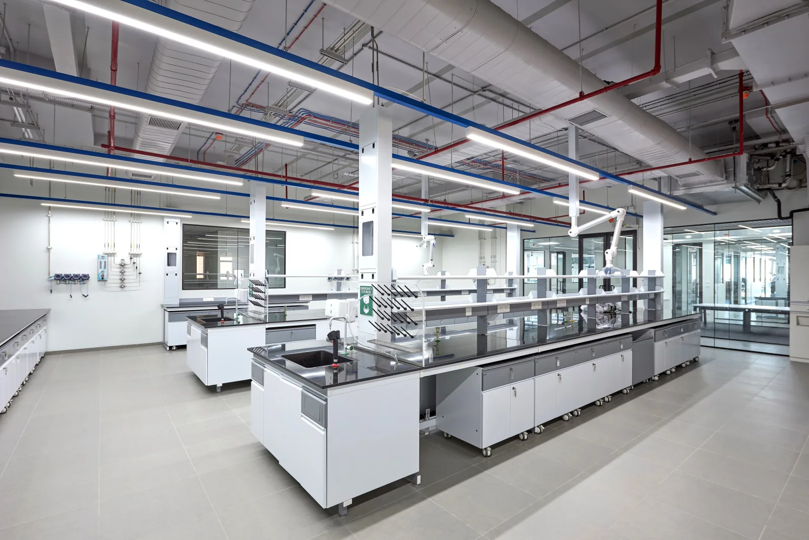 Open-plan analytical laboratory with island benches and colour-coded service pipes