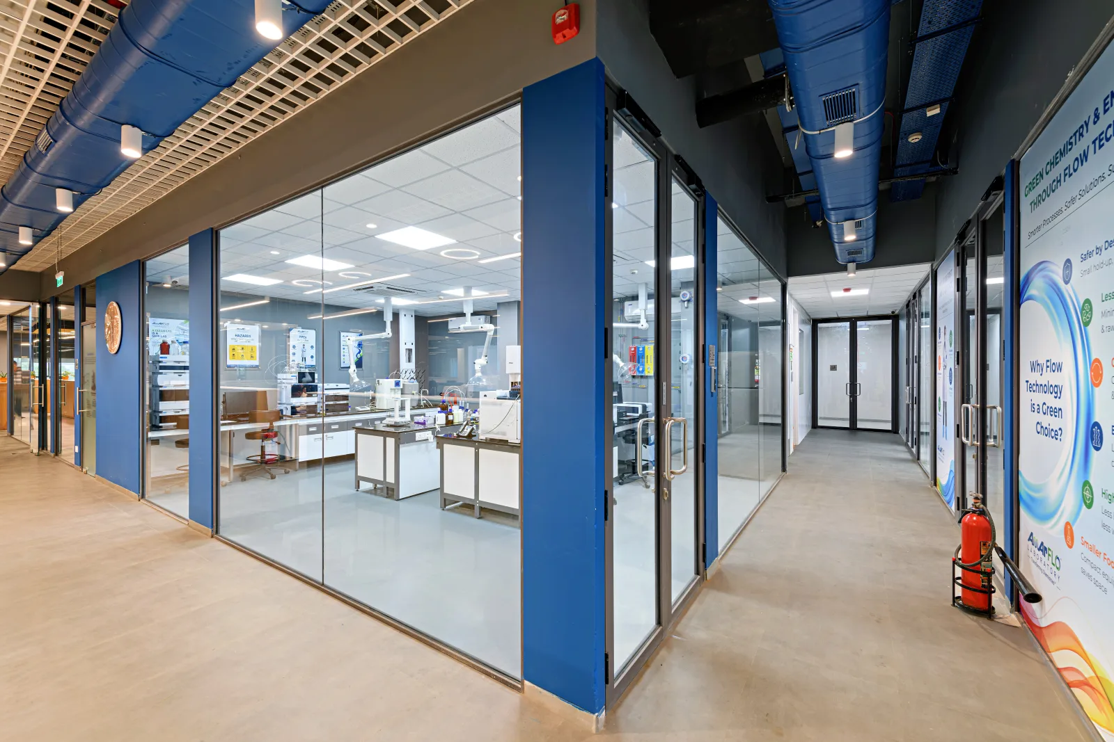 Laboratory corridor with glass-walled labs, blue columns and exposed services